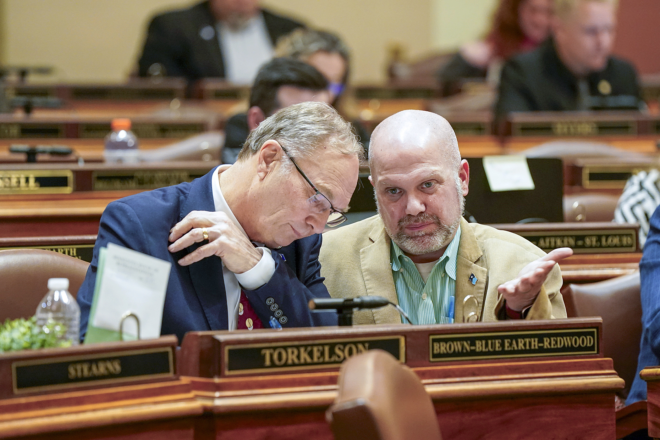 Rep. Paul Torkelson and Rep. Mike Freiberg discuss House business during an evening floor session Thursday. (Photo by Michele Jokinen)